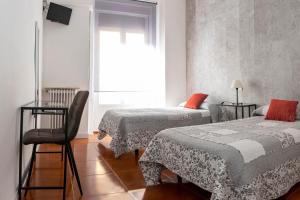 マドリードにあるオスタル トキオのベッド2台、椅子、窓が備わる客室です。