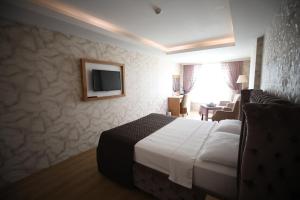 a hotel room with a bed and a tv on the wall at Bayazıt Hotel in İskenderun