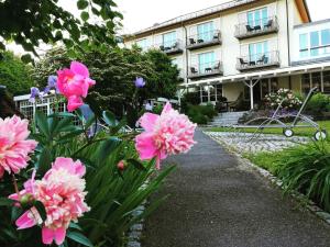 un jardin avec des fleurs roses devant un bâtiment dans l'établissement Hotel Lindenallee, à Lindau