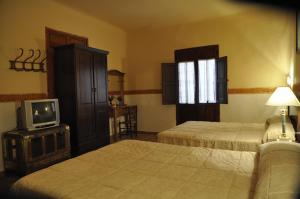 a hotel room with two beds and a tv at Aljibe de Monastrell in Ricote