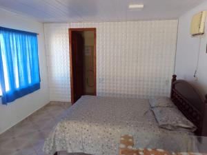 a bedroom with a bed and a blue window at Pousada A Vila do Pirata in Prado