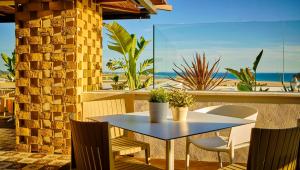 een tafel en stoelen op een patio met uitzicht op het strand bij Hostal Campito in Conil de la Frontera