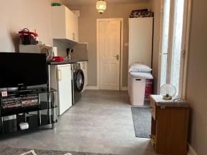 a living room with a tv and a kitchen at Craigellachie Cabin in Aviemore