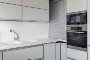 a white kitchen with a sink and a microwave at Mega suite on the sea in Perea