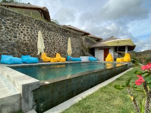 a pool with chairs and umbrellas next to a building at Lombok Khophilauvillas in Kuta Lombok