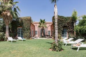 un edificio con tumbonas blancas y palmeras en Villa Pauline with private pool & garden, hotel service and no insight. en Marrakech