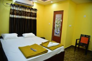 a bedroom with a bed with yellow walls and a chair at Atlantis Beach Resorts in Kumta