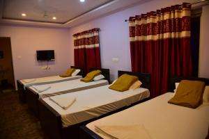 a group of three beds in a room with curtains at Atlantis Beach Resorts in Kumta