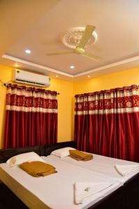 a bedroom with a bed with red curtains at Atlantis Beach Resorts in Kumta