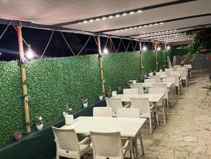 garden alis hotel في فتحية: صف من الطاولات والكراسي بجدار أخضر