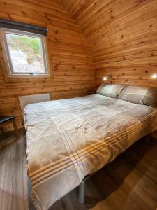 Cama en habitación de madera con ventana en Tarbert Holiday Park, en Tarbert