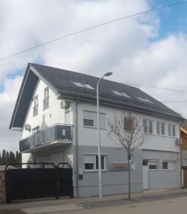 a white house with a black roof and a street light at Dózsaház in Zalaegerszeg