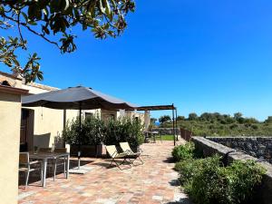 a patio with tables and chairs and an umbrella at La Cantina Villa di campagna in Acireale