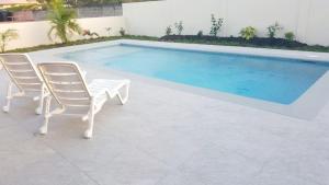 a swimming pool with two chairs and a table next to it at Sea Glass Villa Tobago in Golden Grove