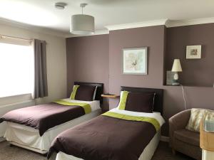 una habitación de hotel con 2 camas y una silla en Fernlea Guest house, en Weston-super-Mare
