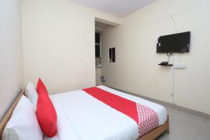a bedroom with a bed with red pillows and a tv at Mannat Residency in Ghaziabad