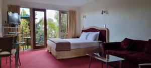 a hotel room with a bed and a couch and a tv at Chantillys Motor Lodge in Taupo
