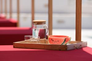 a tray with a drink and a slice of watermelon at Kallisti Paros in Naousa