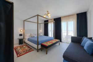 - une chambre avec un lit à baldaquin et un canapé dans l'établissement Kallisti Paros, à Náoussa