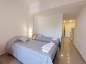 two beds in a white room with a room with a hallway at DELFINA suites 2A in La Rioja
