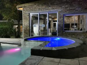 a swimming pool in front of a house at night at Cammy's Guesthouse in Kuilsrivier