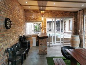 a bar with black chairs and a brick wall at Cammy's Guesthouse in Kuilsrivier