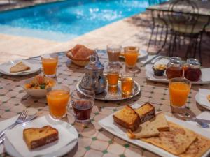 Villa Katia في El Harkat: طاولة مع أطباق من الطعام وكؤوس من عصير البرتقال