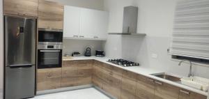 a kitchen with wooden cabinets and a stainless steel refrigerator at Minute walk to the sea in Żebbuġ