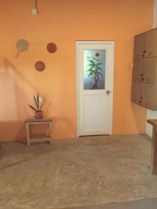 Habitación con pared de color naranja, puerta y mesa. en HappyShack Hostel, en Mirissa