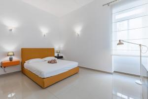 una camera bianca con un letto con una borsa sopra di Unique Four Bedroom Townhouse One Minute Away From The Seafront a Sliema