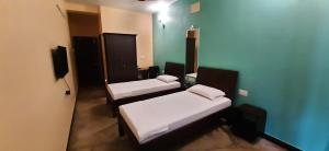 2 camas en una habitación con paredes azules en Chandru De Green, en Chennai