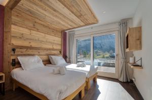 two beds in a room with a large window at Chalet Ancolie in Tignes