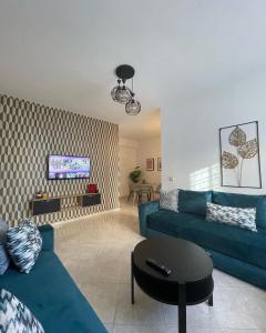 ein Wohnzimmer mit einem blauen Sofa und einem Tisch in der Unterkunft Joli appartement au centre d'Oujda in Oujda