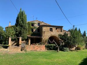 uma antiga casa de pedra com um arco num quintal em Can Carreras em Monells