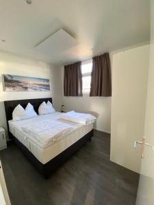 1 dormitorio con 1 cama con sábanas y almohadas blancas en LUXUS Cube Ferienhaus Chalet am See mit Schwimmbad in Lathum NL, en Lathum