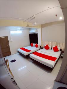 2 camas en una habitación de hotel con almohadas rojas en Hotel Nawanagar Residency, en Jamnagar