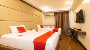 a hotel room with two beds and a desk at RedDoorz Premium @ West Avenue Quezon City in Manila