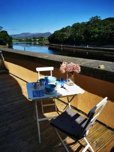 una mesa y una silla en una terraza con vistas al río en sleeps 4 balcony overlooking harbour Walkers /cyclists /water paradise, en Westport