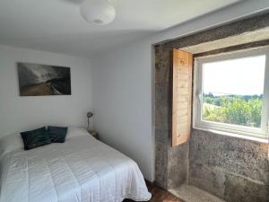 ein Schlafzimmer mit einem Bett neben einem Fenster in der Unterkunft A Casa do Portal in Campo Lameiro