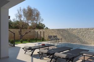 a patio with tables and chairs next to a pool at Ivory Villa, with effusive design, By ThinkVilla in Perama