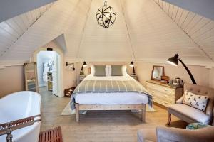 a bedroom with a bed and a chair and a tub at Riverside Inn, Aymestrey in Aymestrey