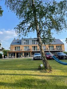 a tree with a hammock in front of a house at Villa nad Zalewem in Dziwnówek