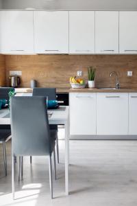 a kitchen with white cabinets and a table and chairs at Apartamenty-Kudowa z pięknym widokiem i balkonem in Kudowa-Zdrój