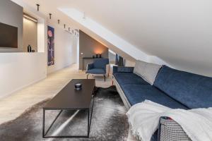 een woonkamer met een blauwe bank en een tafel bij Jonas Mekas Alley Apartments - Jono Meko Skersvėjis in Vilnius