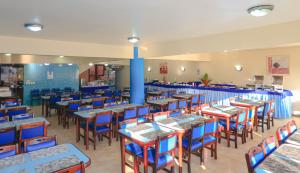 a dining room with tables and blue chairs at Boulevard da Praia Flats in Porto Seguro