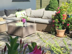 un patio con sofá, mesa y flores en 4 person holiday home in Dronningm lle, en Dronningmølle