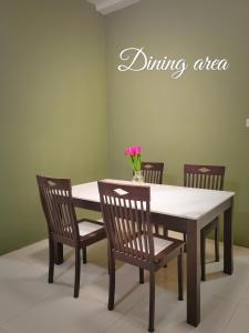 d'une table à manger avec des chaises et un vase de fleurs. dans l'établissement Cozy Homestay (Beside Emart Batu Kawa), à Kuching