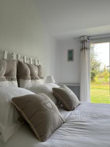 Un dormitorio con una cama blanca con almohadas y una ventana en Maison chaleureuse Spa privé, 