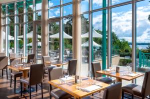 a restaurant with tables and chairs and large windows at Precise Resort Bad Saarow - Golf & Spa in Bad Saarow