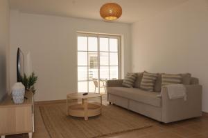 ein Wohnzimmer mit einem Sofa und einem Tisch in der Unterkunft Apartamento Formosa Mar by YHA in Cabanas de Tavira